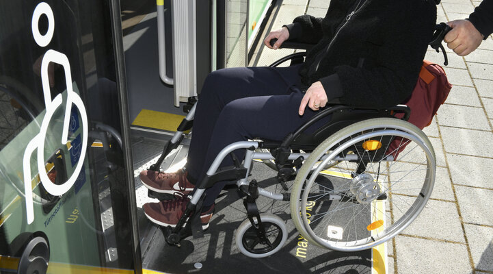 Eine Rollstuhlfahrerin wird über die Rollstuhlrampe in einen Bus geschoben